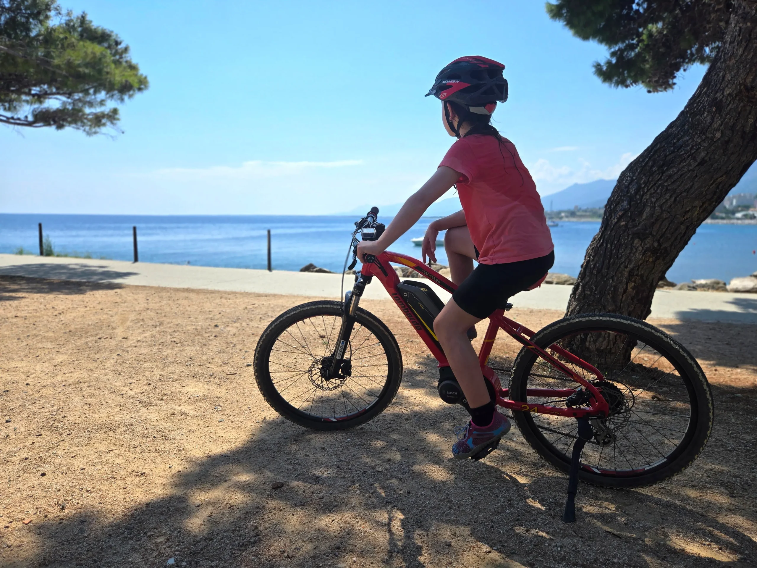 Enfant à vélo électrique au bord de la mer en Corse — location de vélo XP Orizonte